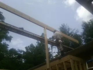 Carpenter setting a ridge beam over a new addition frame — Ice Dam Removal by Roofing Brothers in Uvalde