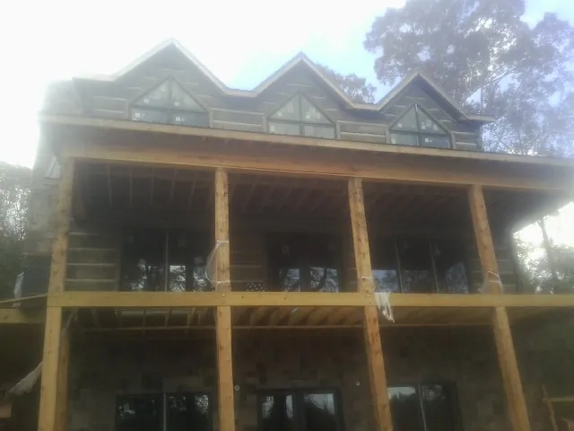 Dormers and porch framing on a large log home under construction — Roof Coating work by our crew in Uvalde