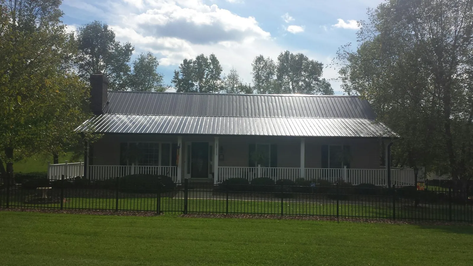 Gray metal roof on a brick ranch with a full width front porch — Gutter Guard Installation work by our crew in Uvalde