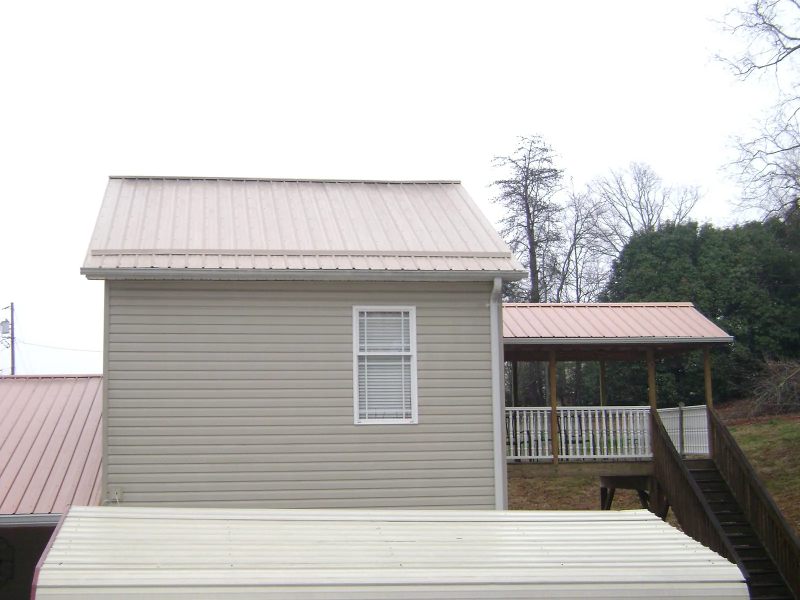 Tan metal roofs on a two story addition and attached porch, from a Roof Replacement job in Uvalde