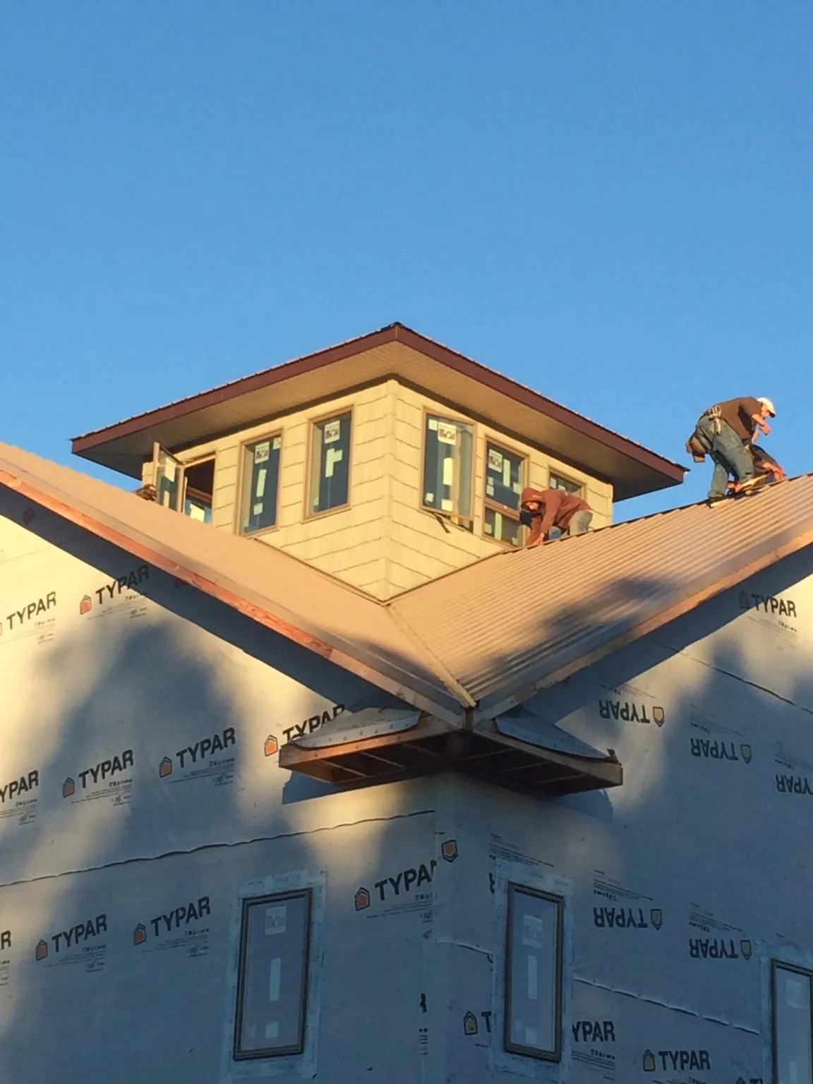 Roofers working around a rooftop cupola on a new metal roof at sunset — Roof Waterproofing in Uvalde by Roofing Brothers